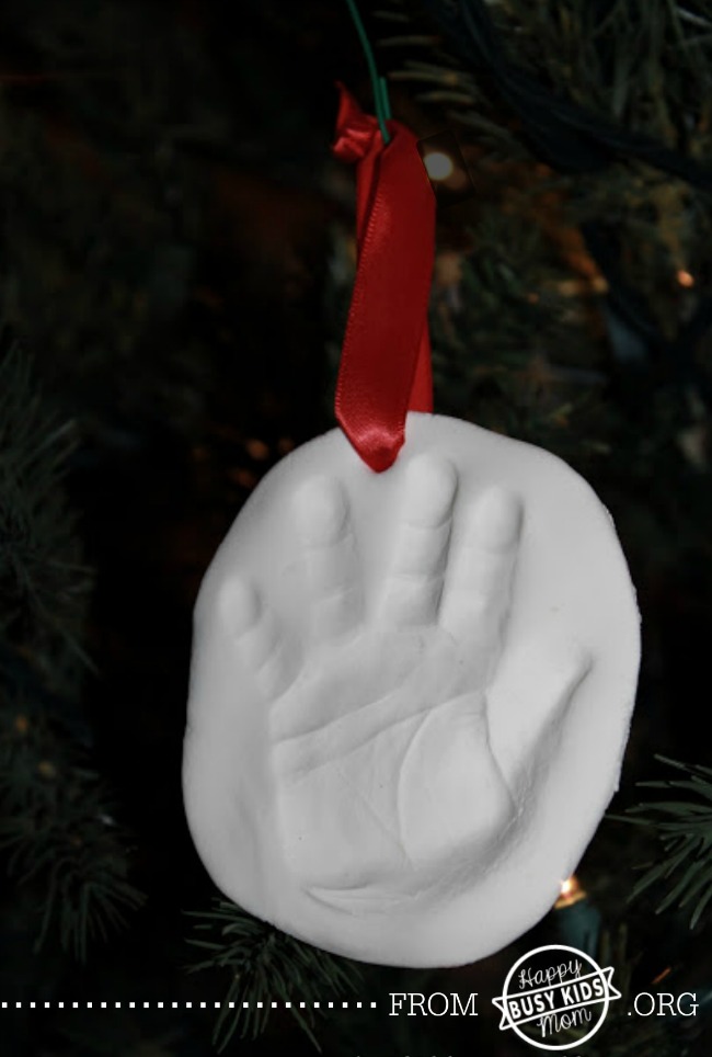Keepsake Handprint, white salt dough with a little handprint hung on a tree with red ribbon.